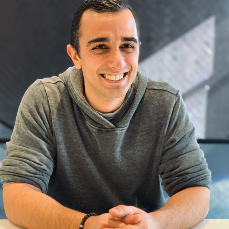 Aris Agdere smiling in a gray sweater