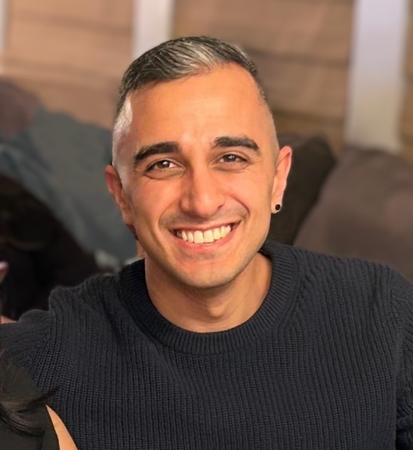 Aris Agdere smiling in a dark sweater